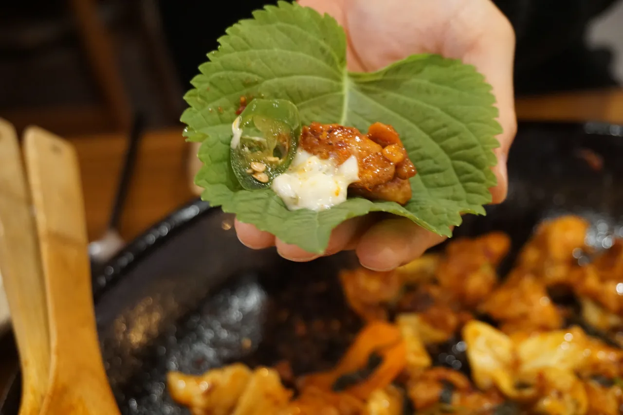 깻잎에 닭갈비를 싸서 먹는 모습